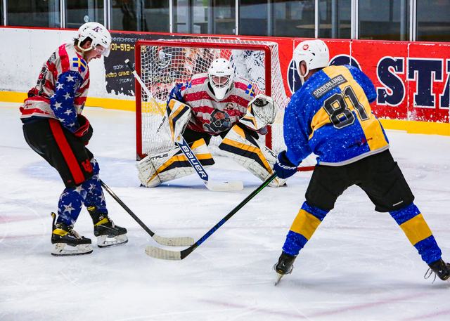 A goal-mouth scramble with three players converging on the crease