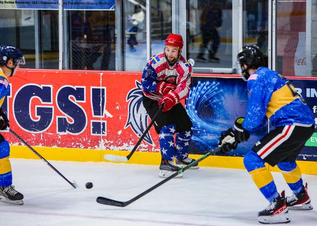 A puck battle along the red boards between a USA and a Sweden skater