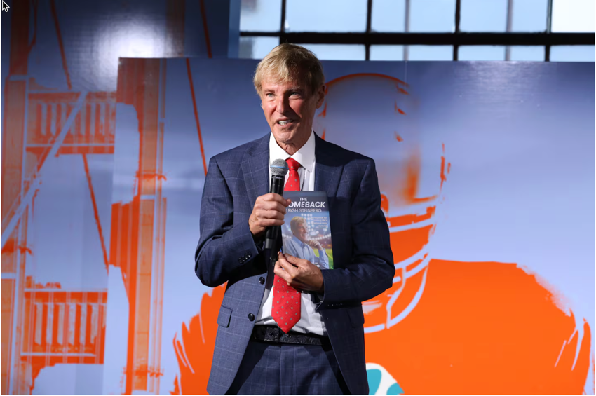 Leigh Steinberg holding a book at a podium