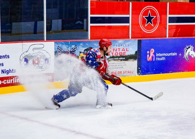 A skater sprays snow with a hard stop in front of the boards