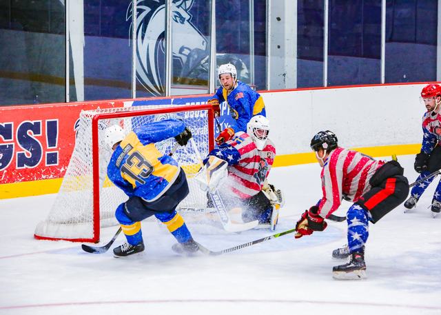 A crowded net-front battle as the goaltender covers the puck