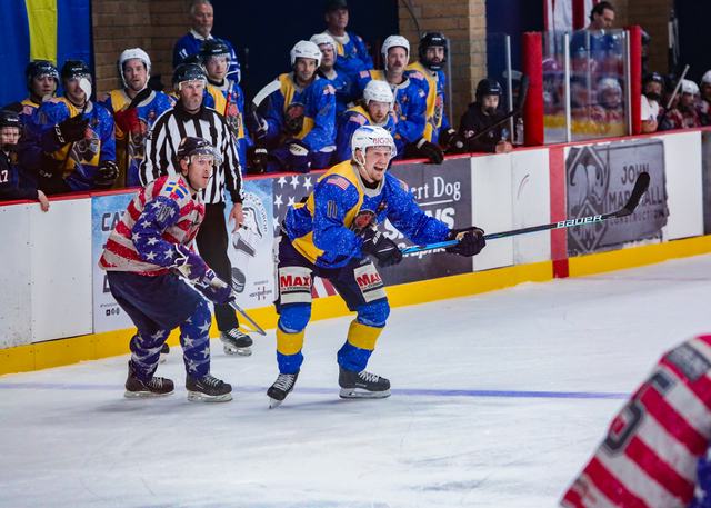 An official trails the play as Sweden and USA skaters battle for position