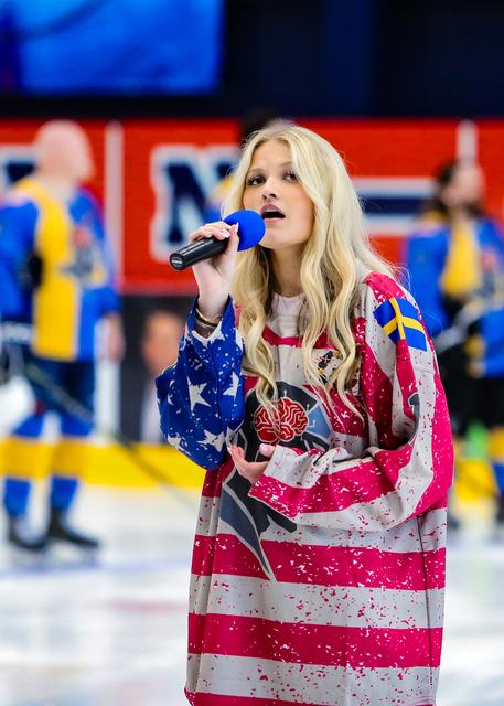 A vocalist in a stars-and-stripes jersey performs the national anthem at center ice