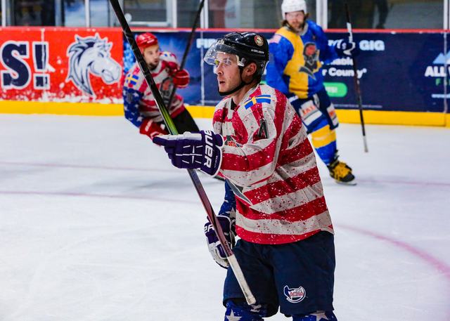 A USA player in a striped jersey drives toward the middle of the ice