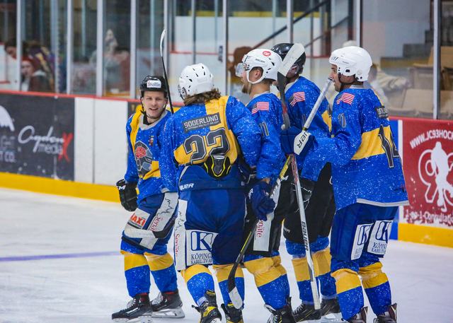 The Sweden team piles together in celebration along the boards